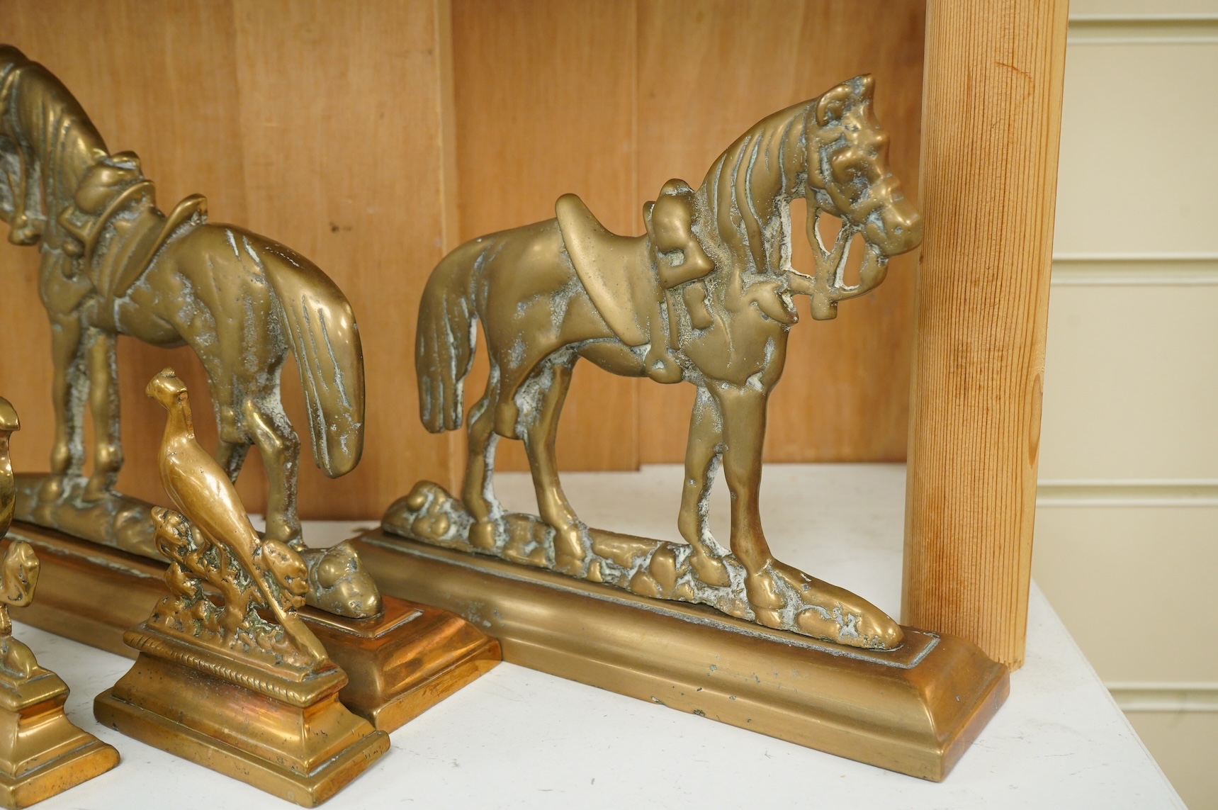 A bronze figure of a horse, two pairs of brass doorstops and a similar pair of candlesticks, 25cm